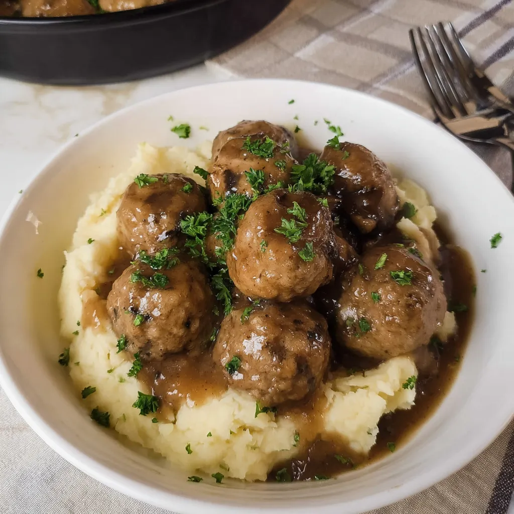 A bowl of meatballs with gravy.