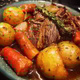 A plate of food with potatoes, carrots, and beef in a brown sauce.