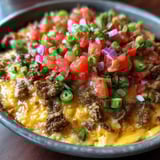 A bowl of food with tomatoes, onions, and peppers.