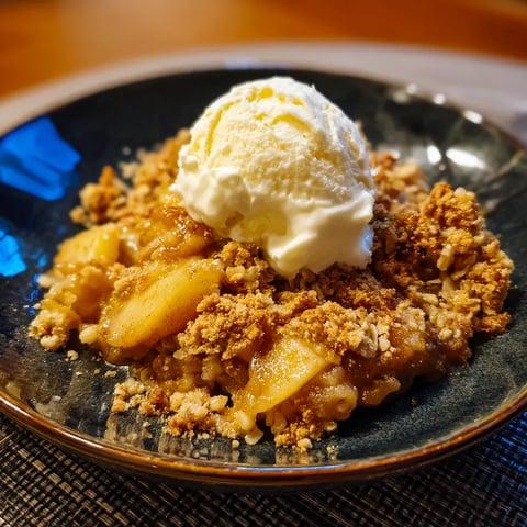 A bowl of apple crisp with a scoop of ice cream on top.