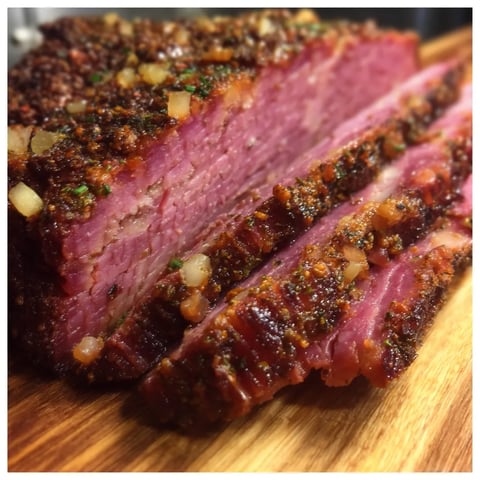 A slice of corned beef on a wooden cutting board.