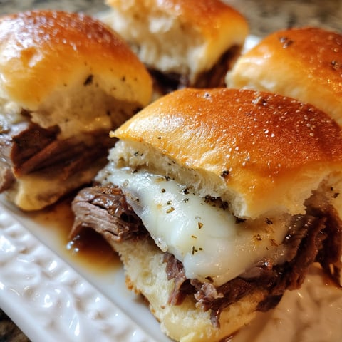 French dip sliders on a white plate.